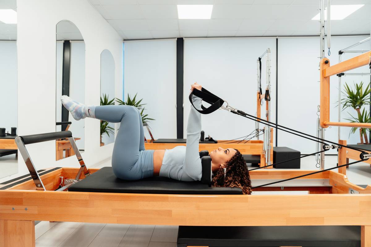 Woman performing Pilates on Reformer machine demonstrating is pilates good for strength training